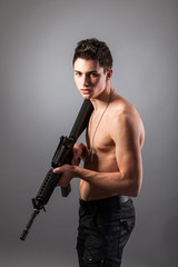 Handsome bare-chested soldier is holding a rifle