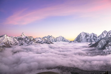 Bergdal gevuld met krullende wolken bij zonsopgang. Himalaya.