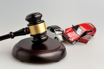 Hammer of judge with models of car accident on gray