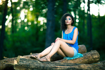 Beautiful Young Woman sitting on log posing