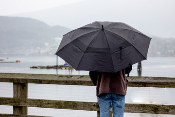 Man with open umbrella on the pier.