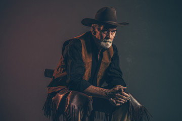 Cigarette smoking old rough western cowboy with gray beard and b