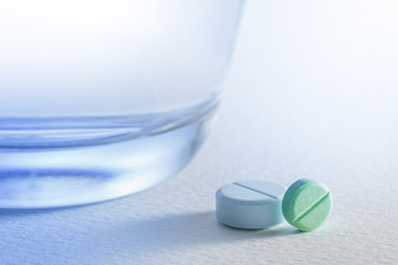 Glass of water and  pill on white background,with light blue.