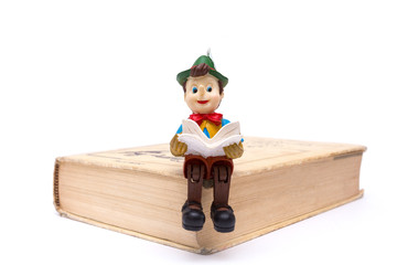 Pinocchio sitting on book isolated on white background
