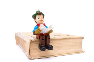 Pinocchio sitting on book isolated on white background