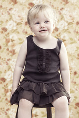 Young girl on stool looking away, smiling