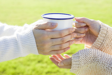 The hands of women who receive a mug