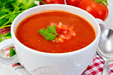 Soup tomato with spoon on napkin and board