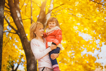 mother and her baby have fun in the autumn park