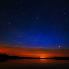 Naklejka premium Morning dawn on a starry background sky reflected in the water o