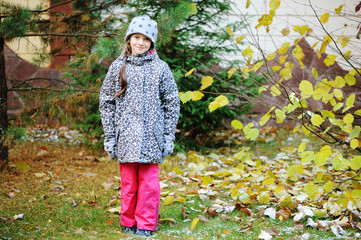 Kid girl has fun in garden with first snow