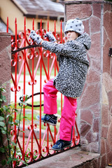Fototapeta na wymiar Kid girl climbed on a fence