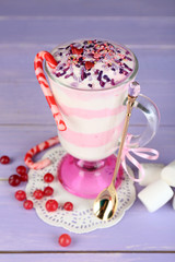 Cranberry milk dessert in glass, on color wooden background