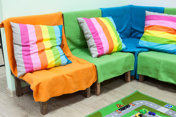 Corner sofa with colorful striped pillows in the room