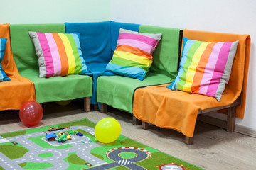 Children's room with bright sofa, toys and balloons on floor