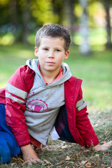 Beautiful boy in red jacket looking at camera outdoors