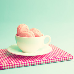 Pink macaroons in a tea cup and vintage book