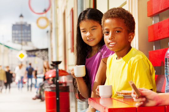 African boy and Asian girl sitting outside in cafe
