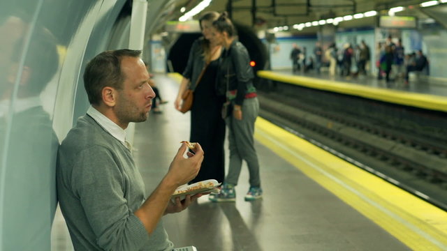 Man eating croissant in the metro station, steadycam shot