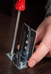 Fixing furniture fittings,  screwing screws using a hand screwdr
