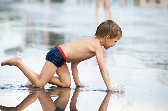 Little boy crowls  in puddle