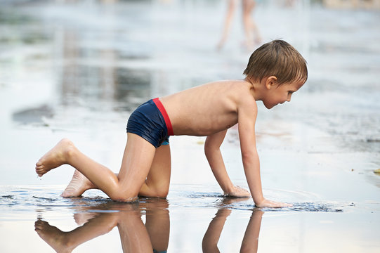 Little boy crowls  in puddle