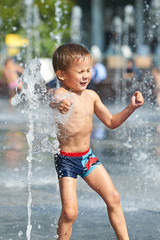 Happy kid playing in a fountain