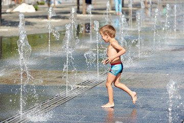 Happy kid running in a fountain