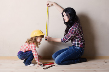 mother with little girl plays in the builder