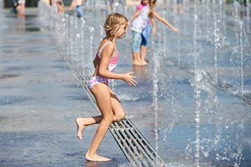 Little girl running among fountains