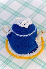 Knitted doily on the teapot in  natural background.