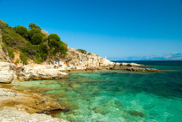 Rocky Kassiopi Beach, Corfu Island, Greece. Sunbeds and umbrella