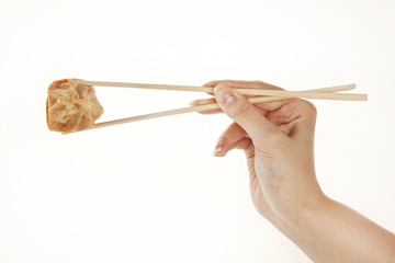 Hand holding chinese Wonton dumpling with chopsticks