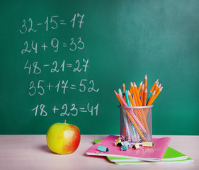 School supplies on table on board background