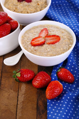 Tasty oatmeal with strawberry on table close-up