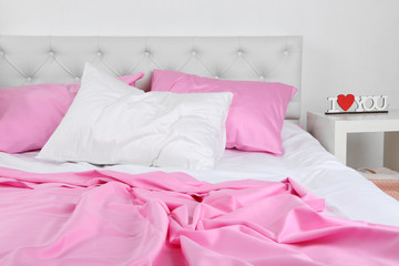 Fototapeta na wymiar Crumpled pink linen on bed