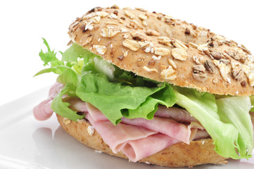 brown bagel filled with ham and lettuce mix