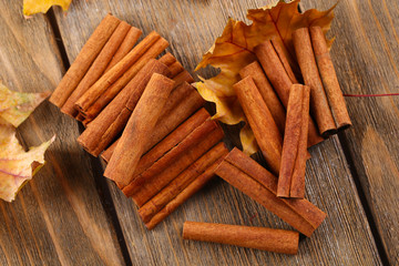Cinnamon sticks with yellow leaves on wooden background