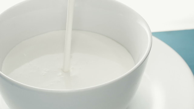 Milk pouring into a white bowl