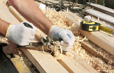 Man hands with carpenters plane on wooden background