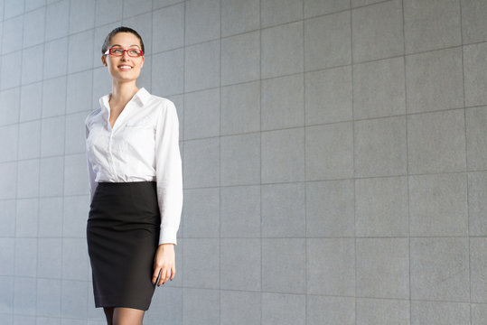 Portrait of a young business woman standing on a gray background