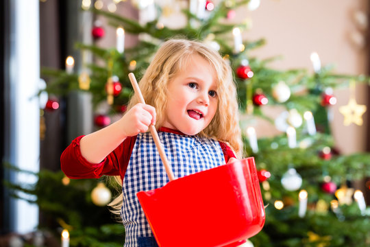 M&auml;dchen backt in der K&uuml;che Kekse vor Weihnachtsbaum 