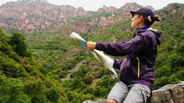 Young woman reading map on trial in mountains