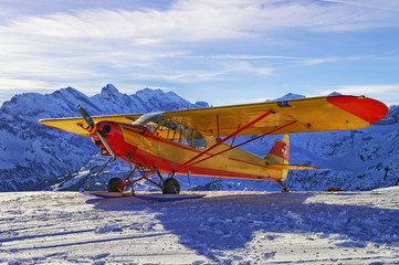 Yellow red airplane at the mountain airfield in swiss alps