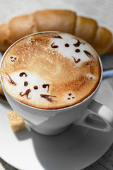 Cup of coffee with cute drawing on table, close up