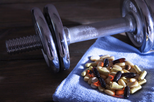 Dumbbell, towel and colorful pills, tablets,