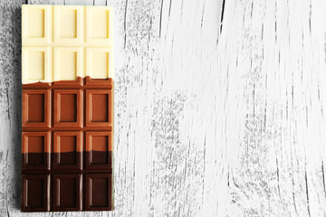 Milk chocolate bar on color wooden background