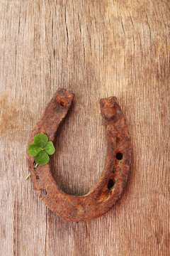 Old horse shoe,with clover leaf, on wooden background