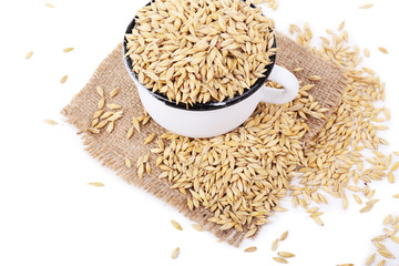Oat in metal mug on sackcloth napkin isolated on white