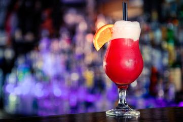 Red cocktail with a slice of orange